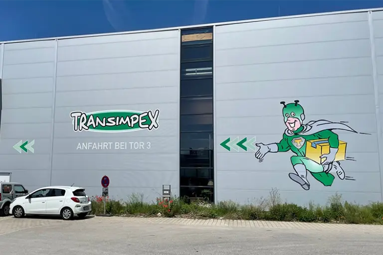 Außenansicht einer Lagerhalle mit Transimpex Logo und T-Mann.