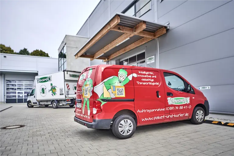 Ein roter Transporter im Vordergrund mit T-Mann und Transimpex-Logo draufgedruckt.